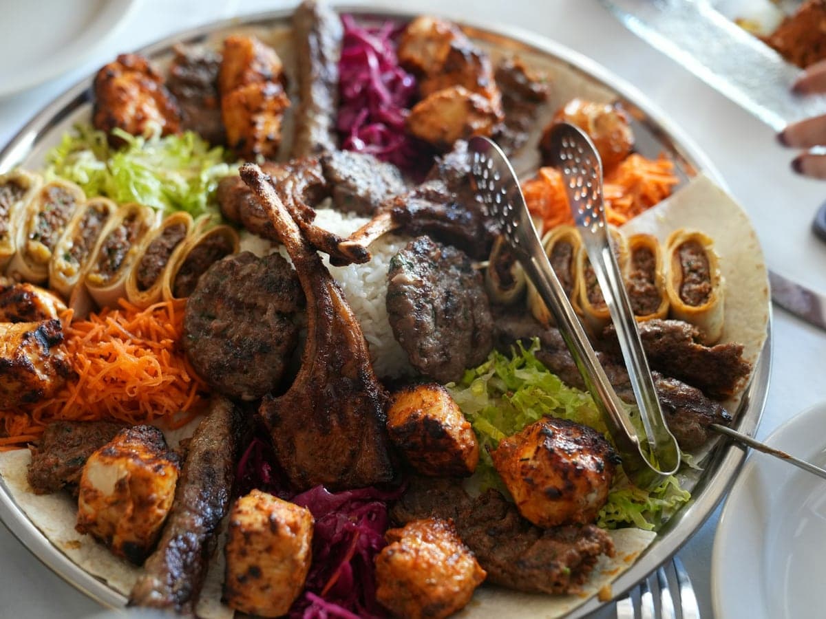 Große Platte mit gemischten Grillspezialitäten, Salaten und Servierbesteck