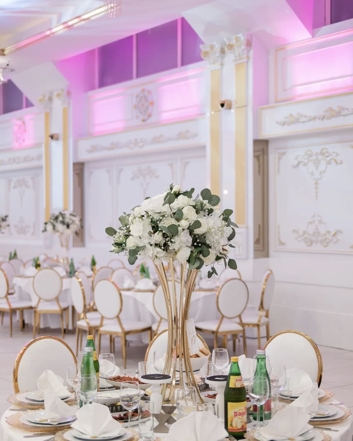Saal von AHUEVENT in Wien mit festlich eingedeckten Tischen, goldenen Stühlen und Blumenarrangements